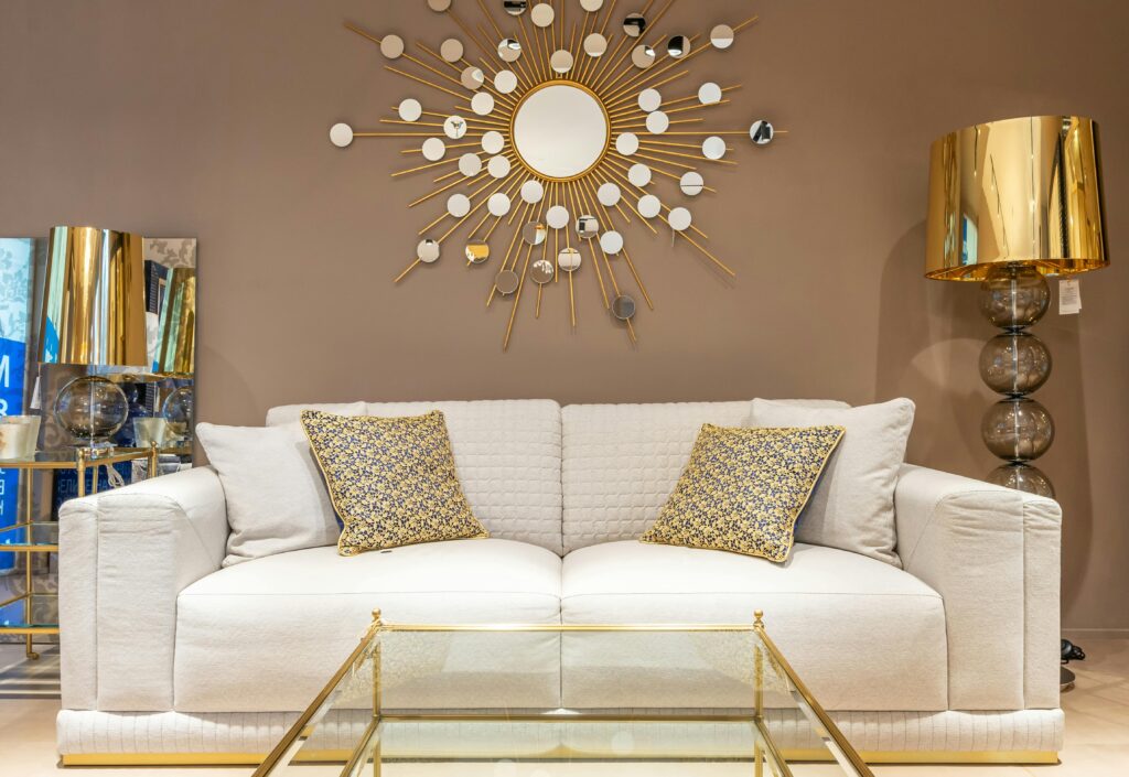 Creative Home Styling & Garden Décor Ideas for a Beautiful Lifestyle A contemporary living room featuring a stylish sofa with gold decor elements and a sunburst wall mirror.