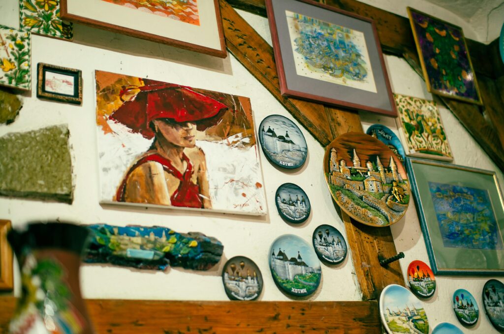 Create a Beautiful Living Space Inside and Out A collection of colorful paintings and decorative plates displayed creatively on a wooden wall.