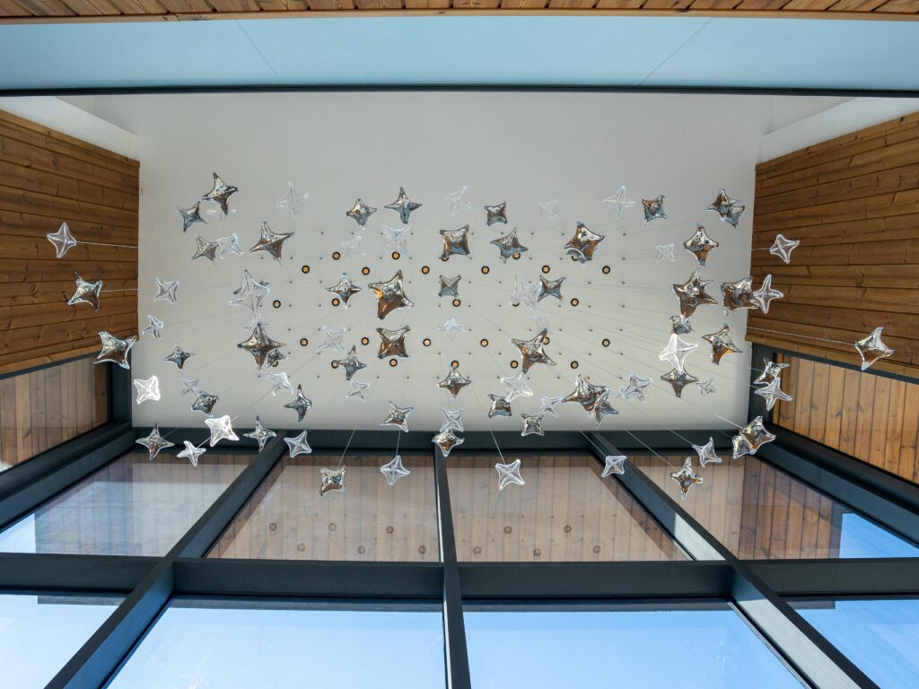 A ceiling installation of star-shaped decorations in a modern interior space.