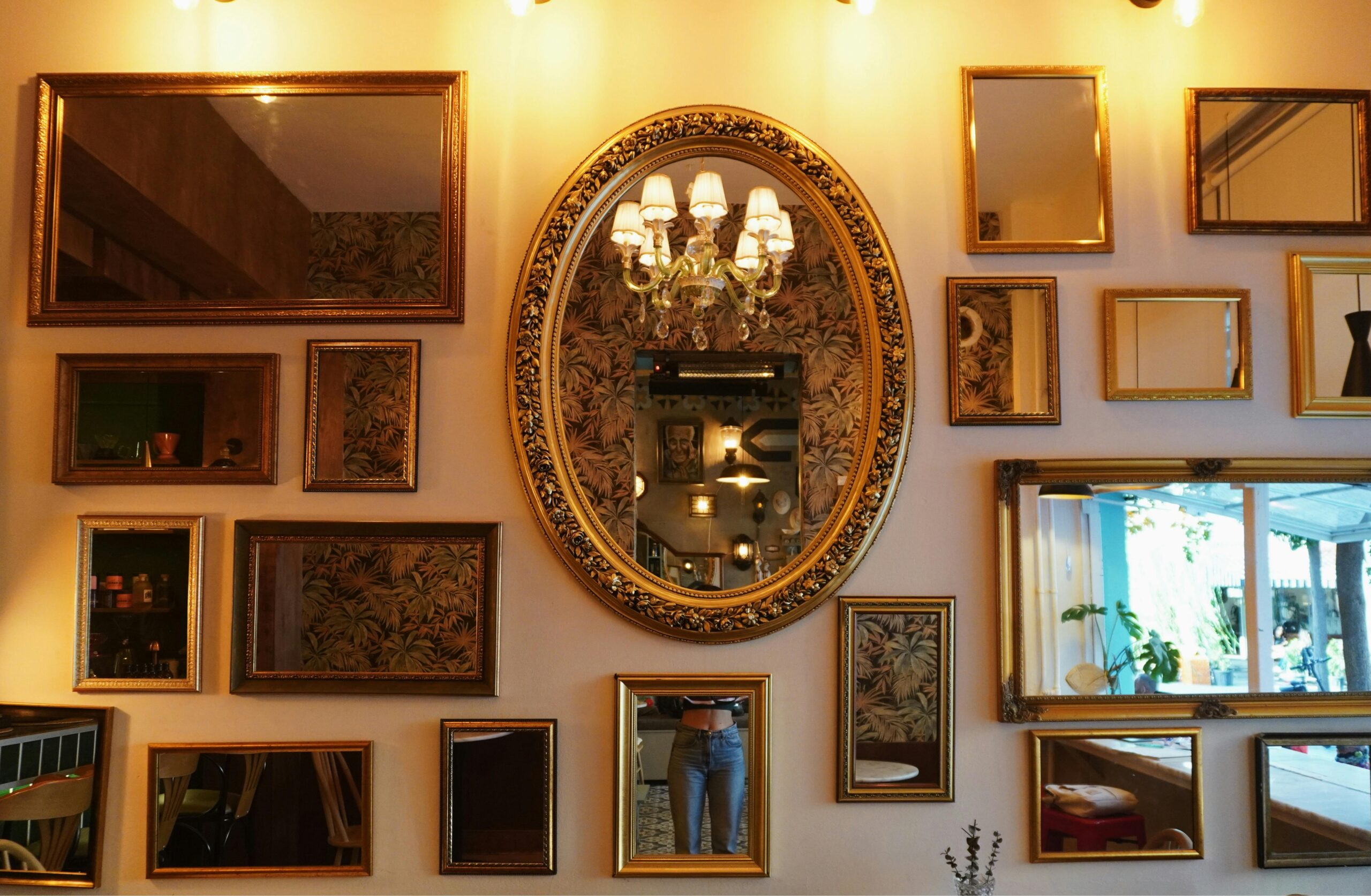 Charming café wall adorned with a variety of framed mirrors and a chandelier.