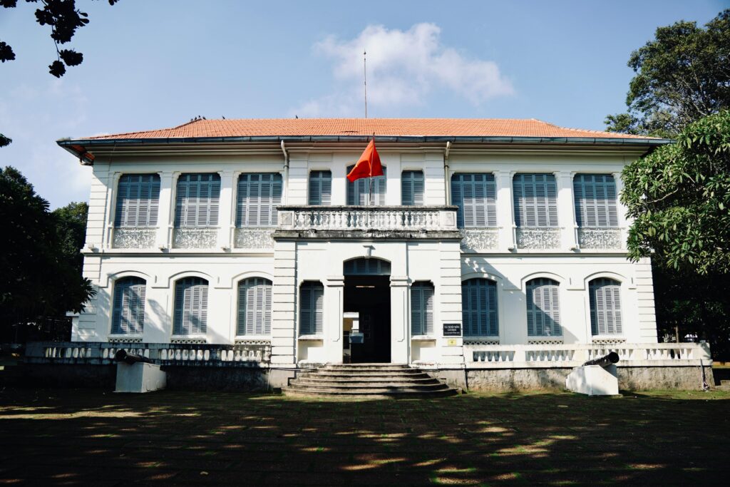 A colonial-style building with red roof and Vietnam flag on a sunny day.