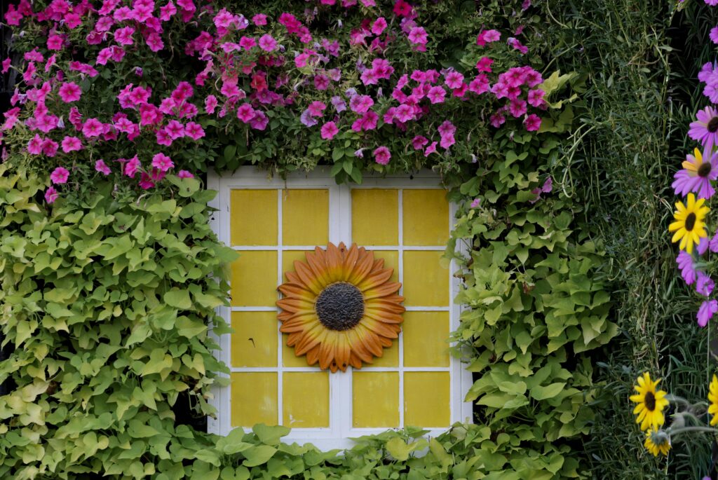 Creative Home Styling & Garden Décor Ideas for a Beautiful Lifestyle Colorful garden window framed by flowers and vines with a sunflower design centerpiece.