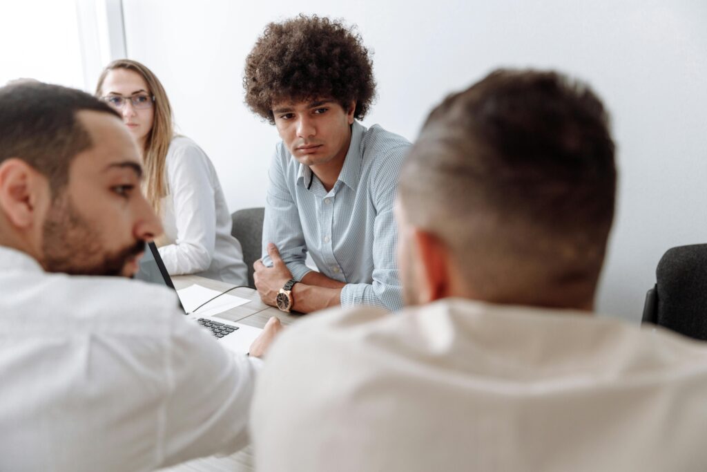 A diverse group of business professionals engaged in a meeting within a modern office setting.