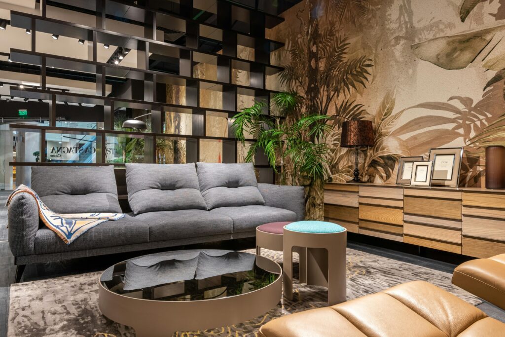 Stylish living room featuring a plush sofa, mirrored table, and tropical-themed wallpaper.
