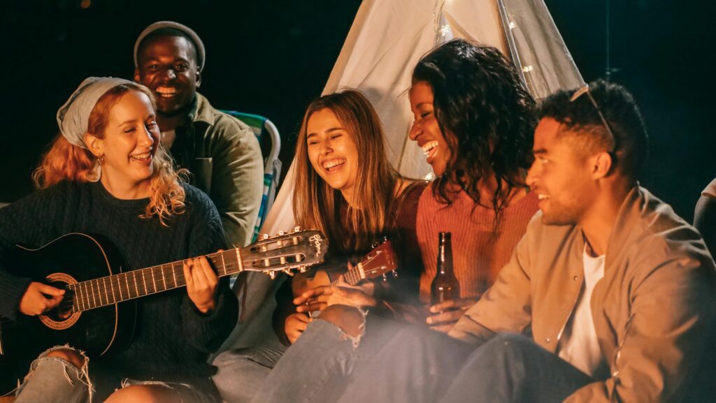 A Complete Guide to Stylish Home Decor A diverse group of friends playing guitar and ukulele by a campfire at night, having fun and socializing.
